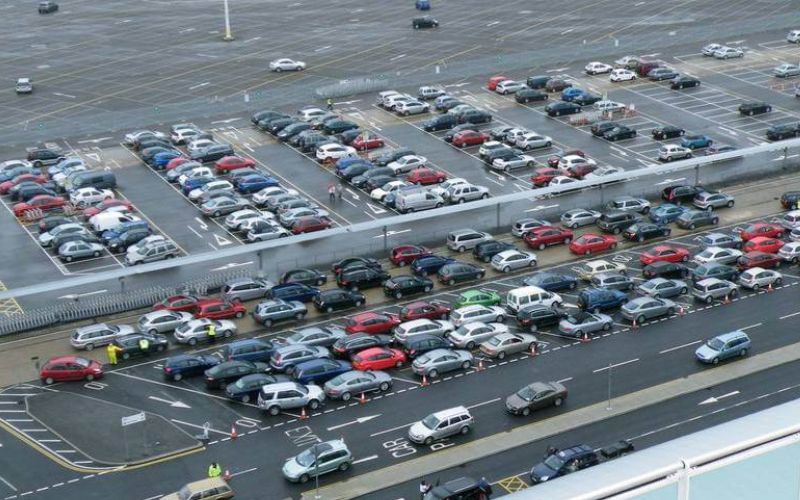 Aerial view of a busy parking lot at the Southampton cruise terminal, with rows of parked cars in various colors, indicating high activity possibly linked to cruise departures or arrivals.