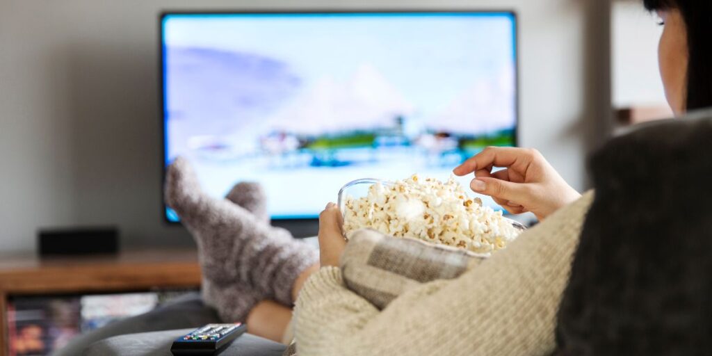 woman watching a tv show while eating popcorn
