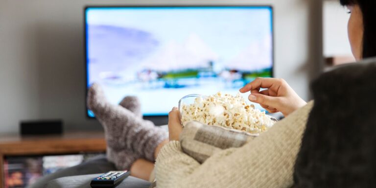 Woman watching a tv show while eating popcorn