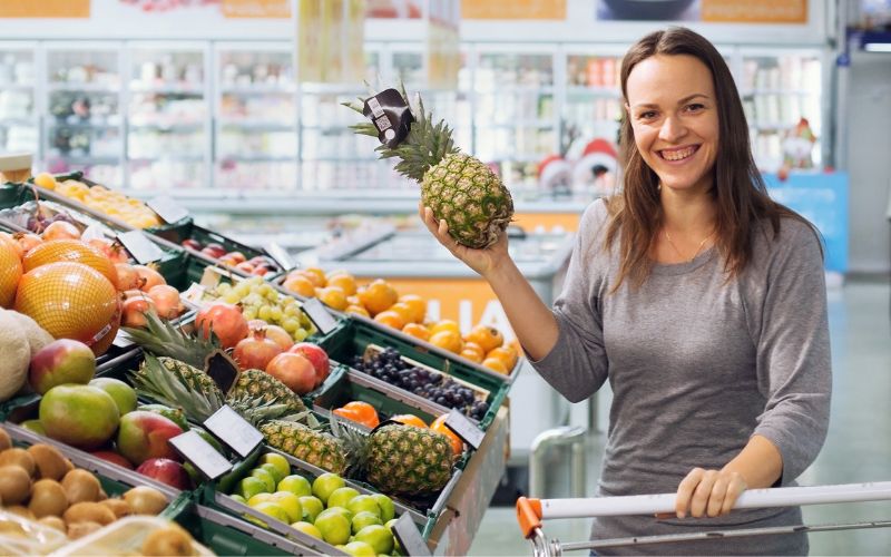 Woman with pineapple in supermarket